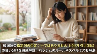 韓国語の学習者が、教材を見ながら「〜ではありません」の使い分けを勉強しているアイキャッチ画像。記事タイトル「韓国語の指定詞の否定：〜ではありません（-이/가 아니에요）の使い分けを徹底解説！パッチムのルールやスペルミスも解決」が下部に表示されている。