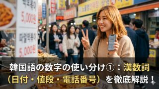 ソウルの活気ある市場で、笑顔でスマートフォン（電話番号表示）とトッポギ（価格表示）を持つ日本人女性。画像下部には、記事タイトル「韓国語の数字の使い分け①：漢数詞（日付・値段・電話番号）を徹底解説！」が文字で入っている。SEOキーワード：韓国語、漢数詞、使い分け、日付、値段、電話番号、徹底解説、アイキャッチ